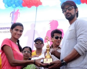 :  Supriya Mali (left) winner of the women’s Half Marathon receives her Trophy and cash award of Rs 20,000 from Chief Guests Bollywood actors Jeetendra (centre) and Kunal Kapoor .